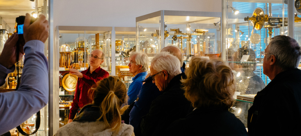 Prof. Franz Sachslehner (links) erläutert den Besuchern der Matinee die historischen physikalischen Geräte. Rechts oben sind Polarisationsapparate zu sehen. Dieser Ausstellungsraum befindet sich neben dem Christian-Doppler-Hörsaal.