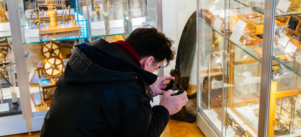 Ein Besucher fotografiert ein besonderes Glanzstück: die analytische Waage von Josef  Nemetz, die 1894 unter Ludwig Boltzmann angeschafft wurde. Genauigkeit 10 mg, Gewichtsauflage von außen mittels Drehhebel.