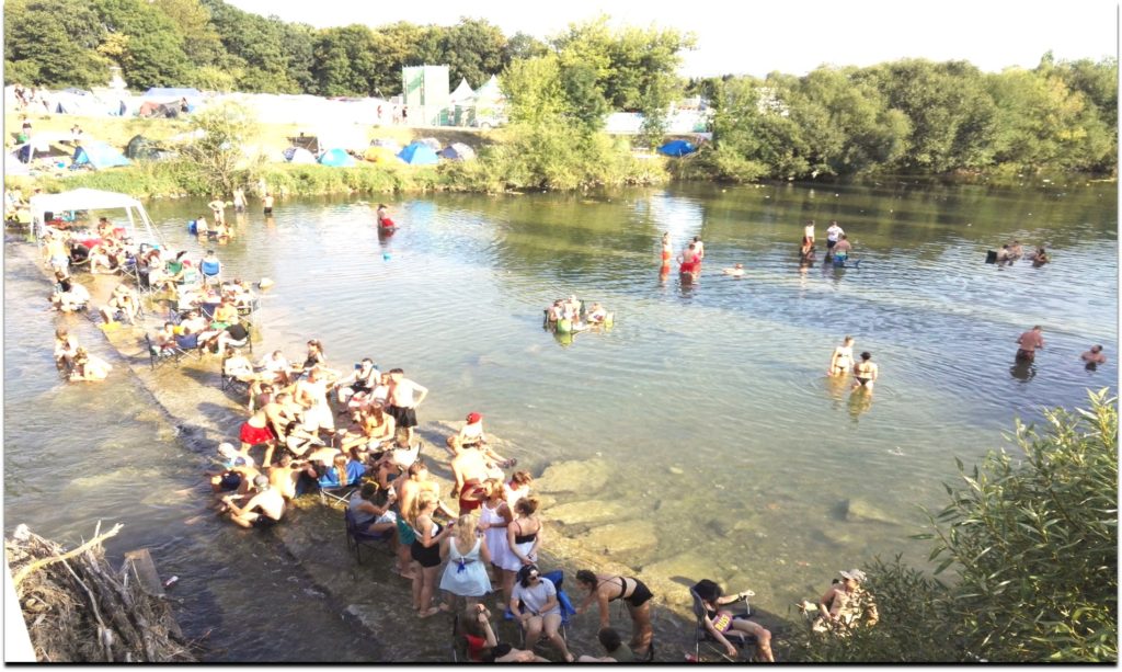 Viele Menschen stehen und sitzen im Fluss.