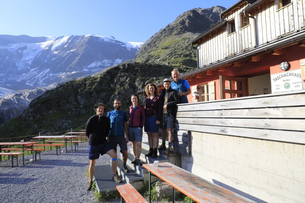 Das Projektteam der Uni Innsbruck (sechs Personen), stehen auf der Treppe einer Hütte vor einer Bergkulisse.