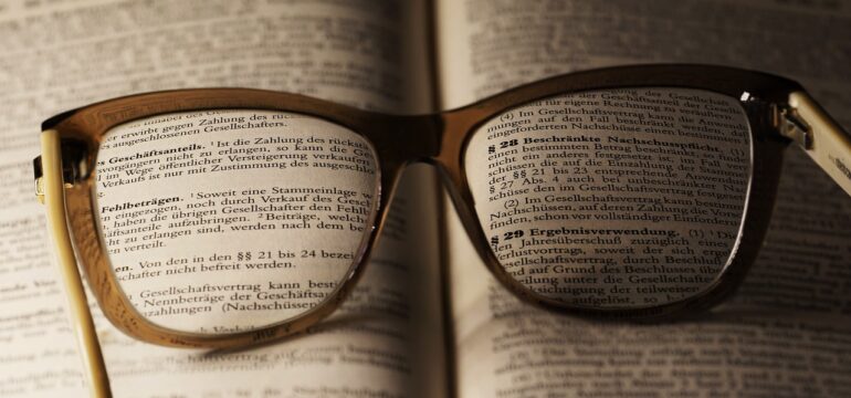 Eine Brille liegt auf einem Gesetzesbuch.