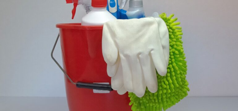 Ein Putzeimer mit Putzmitteln und Handschuhen