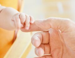 Die Hand eines Babys greift nach der Hand eines Erwachsenen.