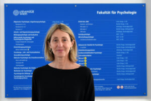 Die Psychologin Giorgia Silani steht vor einem Schild der Fakultät für Psychologie.