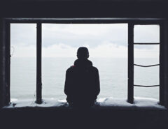 Ein Mann sitzt alleine vor dem offenen Meer.