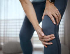 Nahaufnahme einer nicht erkennbaren Frau, die bei einer Übung zu Hause Schmerzen im Knie hat