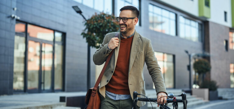 Ein junger Mann steht lachend neben seinem Fahrrad.