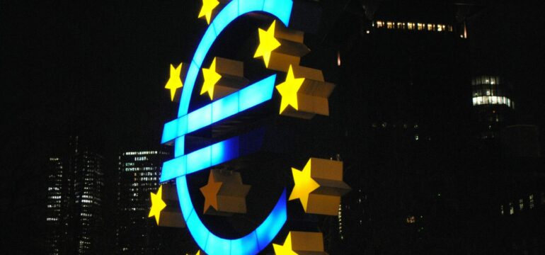 Ein riesiges Euro-Zeichen und Sterne, im Hintergrund Gebäude.
