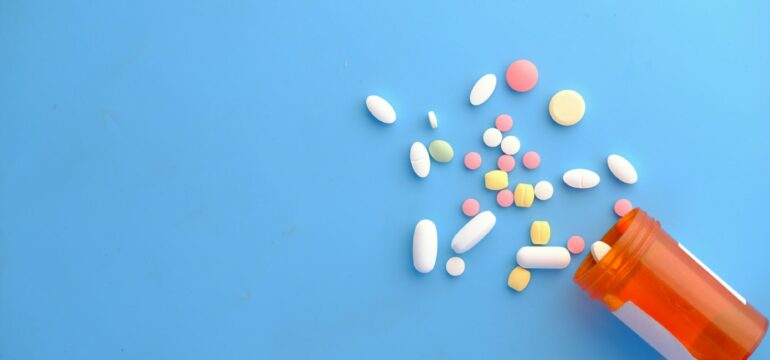 Verschiedene Tabletten fallen aus einer Dose.