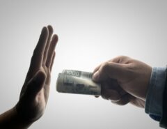 Eine Hand hält einen Geldschein, eine andere Hand lehnt diesen ab.